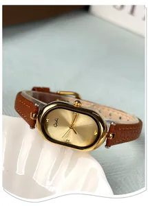 Detail of vintage oval gold watch case with brown leather strap and sunray dial