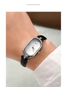 Close-up of vintage oval silver watch with black leather strap on a female wrist