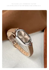 Macro shot of oval silver watch with champagne dial and tan leather strap detail