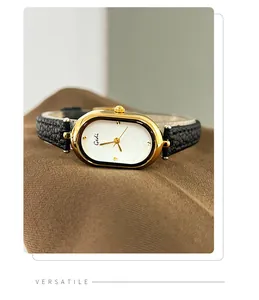 Detailed close-up of golden oval watch case and black leather strap texture