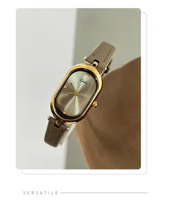 Close-up of vintage oval quartz watch with gold case and grey leather strap for women