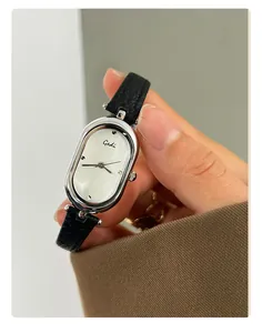 Close-up of a vintage oval silver watch with a minimalist dial and black leather strap