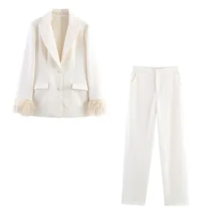 Detail of white suit blazer featuring elegant feather cuffs and straight-leg trousers