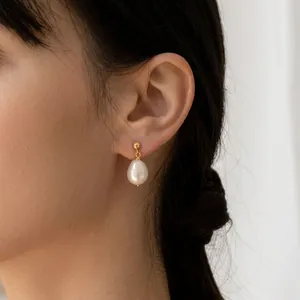 French vintage freshwater pearl drop earrings with golden studs worn by a model