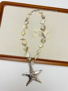 Detail of bohemian shell beaded necklace featuring a silver starfish pendant and lobster clasp