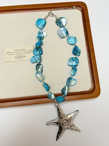Detailed close-up of a silver starfish pendant and blue shell fragment necklace strand