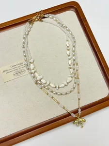 Detail view of multilayer necklaces with pearls, shell beads and golden bow pendant