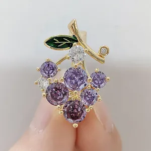 Close-up of a purple crystal grape brooch with green leaves and gold finish detail