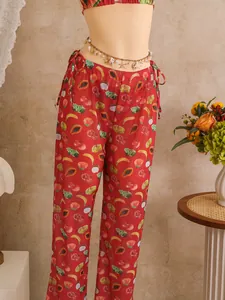 Detail of vibrant tropical fruit print wide-leg pants with decorative shell waist chain