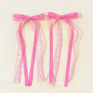 Detail of pink lace ribbon bow hair clips with satin fabric and layered streamers