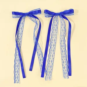 Detail of royal blue lace bow hair clip with long flowing ribbon streamers in pair