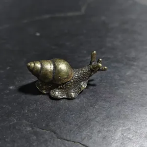 Macro di una statuetta di lumaca in rame con finitura antica su pietra scura