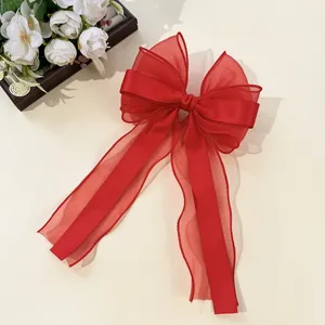 Macro detail of red organza and satin bow hair clip with layered fabric texture