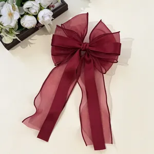 Detailed view of large burgundy double-layer tulle and satin bow hair clip with ribbons