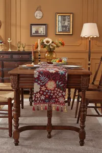 Nahaufnahme des Vintage Jacquard Tischläufers mit roten Quasten auf Holztisch