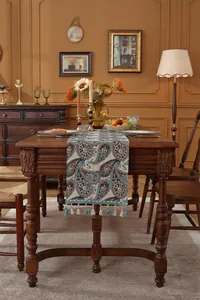 Detailansicht eines Tischläufers mit Paisley-Muster und Quasten auf dunklem Holztisch