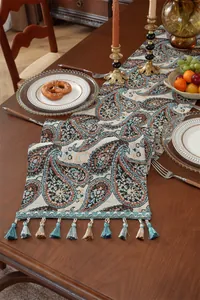 Detail eines Vintage Paisley Jacquard Tischläufers mit dekorativen Quasten auf Holz