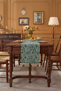 Detail eines grünen Tischläufers mit Paisley-Jacquardmuster und Zierquasten am Rand