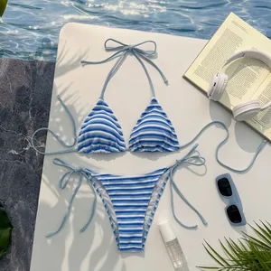 Dettaglio del bikini a righe bianche e blu con laccetti laterali e sfondo piscina