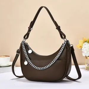 Close-up of brown litchi pattern dumpling bag with silver chain and metal charms