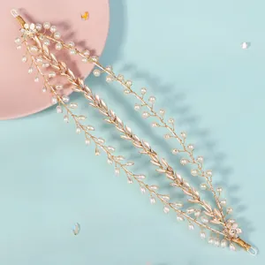 Macro shot of gold bridal hair vine with pearls and metal leaf details on pastel base