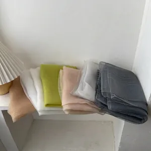 Detail of multi-color semi-transparent silk scarves stacked on a white windowsill