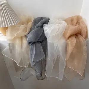 Detail of sheer organza scarves with golden metallic stripes in assorted colors