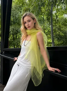 Close-up of lightweight yellow silk scarf paired with a white textured summer outfit