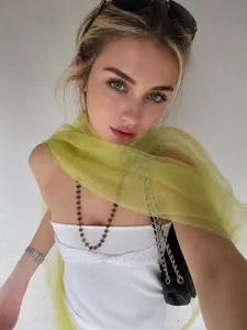 Detail of lightweight yellow silk-like scarf draped on model with beaded necklace
