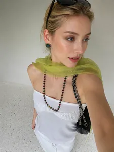 Model wearing translucent green silk scarf with colorful beaded necklace and earrings