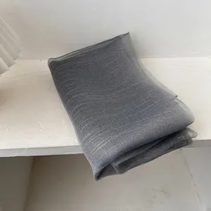 Detail of dark grey sheer silk scarf featuring elegant horizontal gold stripes