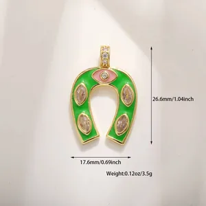 Detail of horseshoe pendant with pink evil eye and green enamel inlay in gold plating