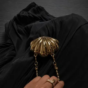 Close-up of a gold shell evening clutch with metallic finish and fine chain strap