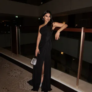 Detail of the high slit and pleated texture on this elegant black one-shoulder evening gown
