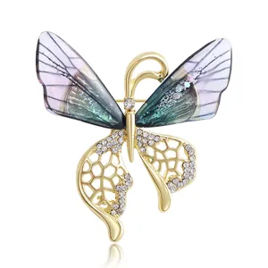 Vue détaillée d'une broche papillon avec ailes dégradées et détails en strass dorés