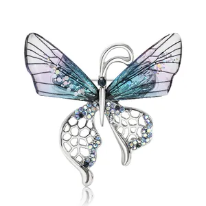 Vue macro d'une broche papillon argentée avec ailes dégradées violettes et strass colorés