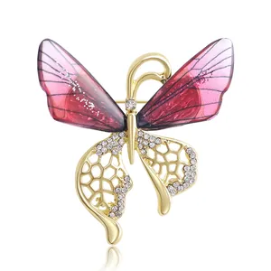 Élégante broche papillon dorée avec des ailes en émail rose et des strass brillants