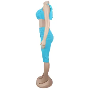 Detailed side view of turquoise two-piece set featuring crop top and pleated skirt