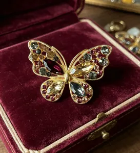 Détail de la broche papillon vintage avec cristaux colorés dans un écrin de velours