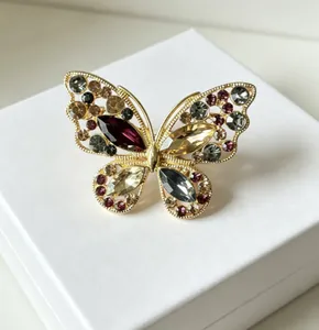 Gros plan d'une broche papillon en alliage doré ajouré sertie de cristaux colorés