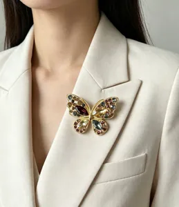 Détail d'une broche papillon évidée avec cristaux multicolores sur un tailleur beige chic