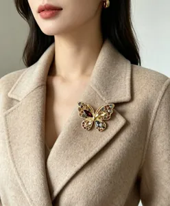 Gros plan d'une broche papillon vintage avec strass colorés sur un manteau en laine beige