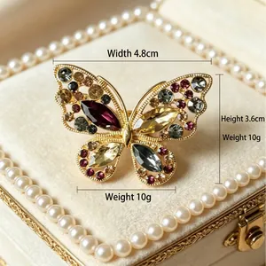 Exquise broche papillon évidée dorée avec strass colorés dans un écrin velours