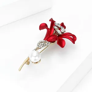 Détail macro d'une broche lys rouge avec strass brillants et perle blanche sur base dorée