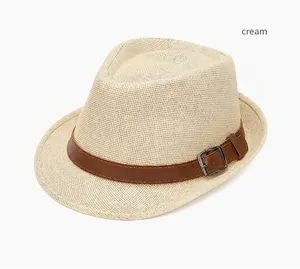 Detail of cream straw fedora hat featuring a brown faux leather band and silver buckle