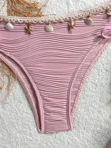 Dettaglio slip bikini rosa a coste con pizzo crochet, conchiglie e ciondoli a stella