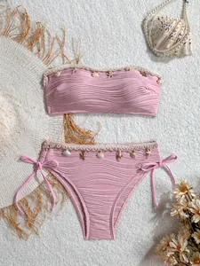 Dettaglio del bikini rosa con decorazioni di conchiglie, stelle marine e tessuto a coste