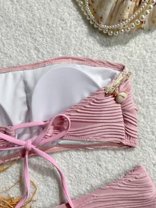 Dettaglio del top bikini rosa a costine con ciondolo a conchiglia e imbottitura