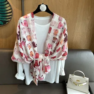 Close-up of colorful cartoon cat prints on a lightweight white cotton linen scarf