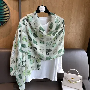 Detail of mint green linen scarf featuring stylish cartoon cat prints and soft texture